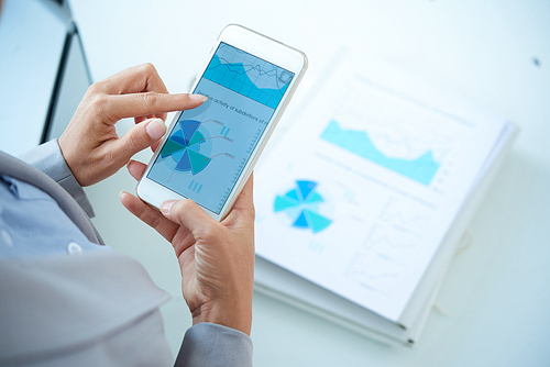 Hands of business person analyzing financial chart on smartphone screen