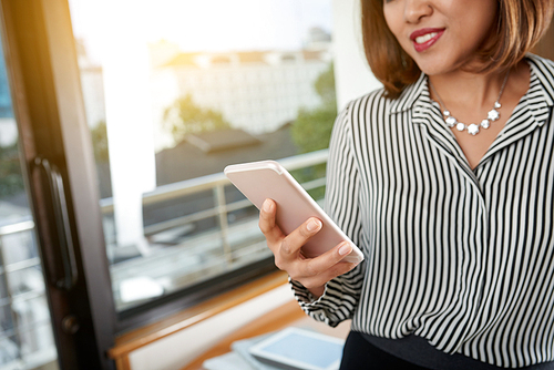 Cropped image of business woman using application on her smartphone