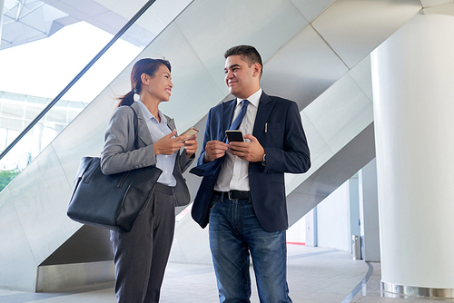 Cheerful multi-ethnic coworkers standing in modern office and talking