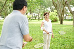 Pretty senior Asian woman playing badbinton with her husband