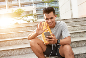 Happy jogger using smartphone to make videocall after training