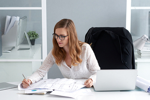 Professional female architect checking blueprint to make final corrections