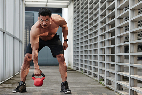 Fit Malaysian man doing exercises with weight