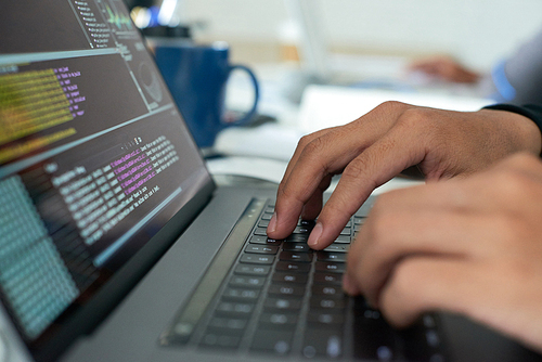 Hands of programmer writing code on laptop