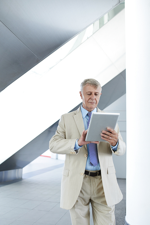 Mature business executive reading important information on tablet computer