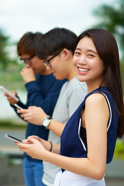 Happy Korean teenage girl with smartphone in her hands