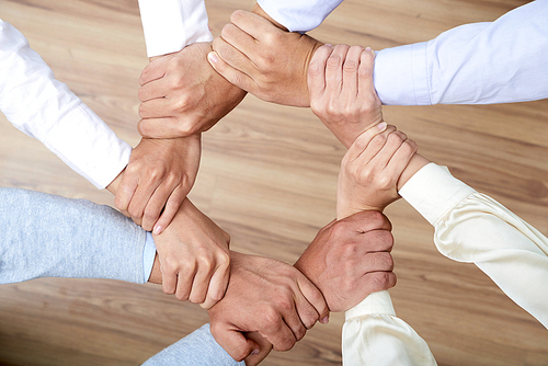Coworkers holding wrists of each others: together we are stronger