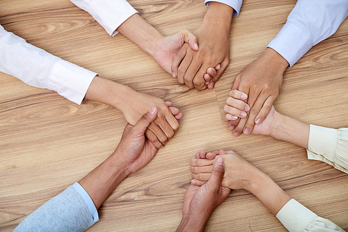 Hands holding each other to show unity, view from above