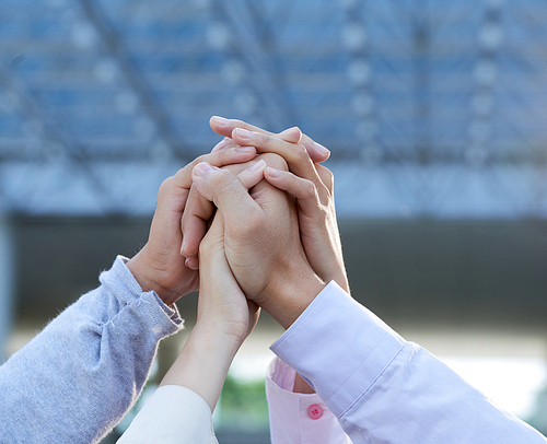 Clasped hands of business people raised to express togetherness