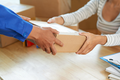 Hands of woman receiving parcel from post worker