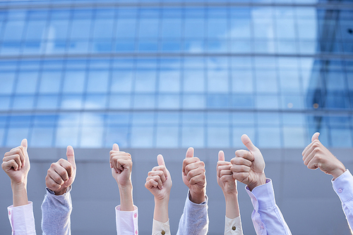 Hands of business people showing thumbs-up to the sky