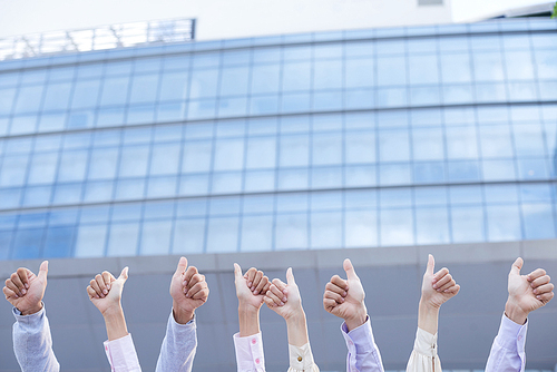 Hands of successful business people showing thumbs-up