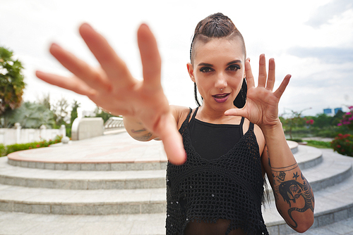 Young woman with tattoos and heavy make-up making gestures with her hands