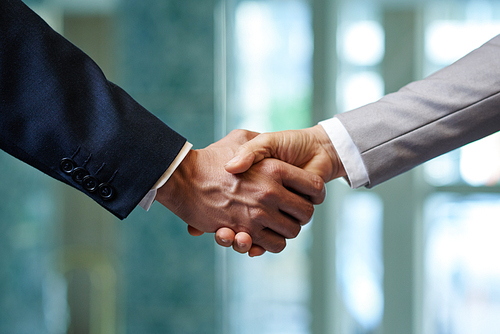 Close-up shot of firm handshake as sign of trusted partnership, blurred background