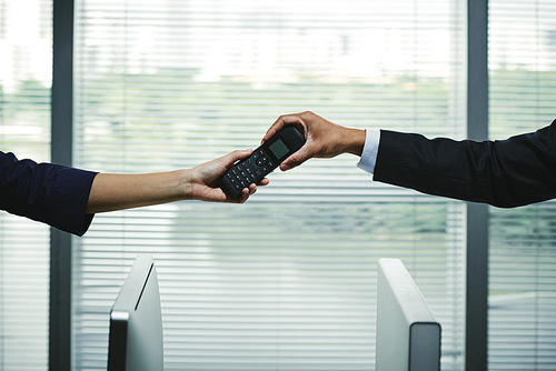 Hands of businesswoman giving telephone receiver to colleague