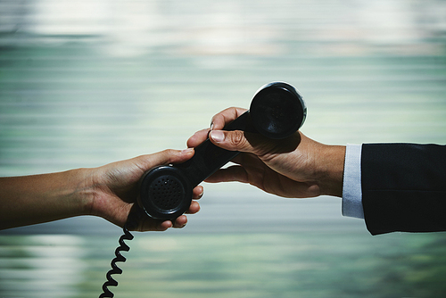 Coworkers passing telephone receiver to each others