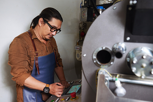 Asian man in glasses managing work of coffee roaster