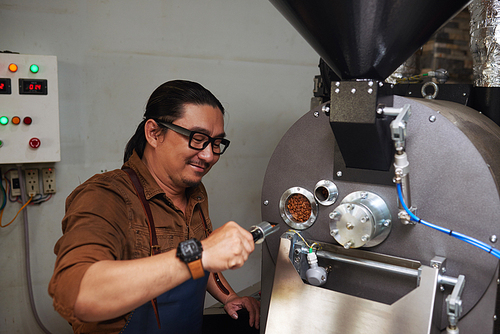 Barrista using modern roaster to prepare coffee beans