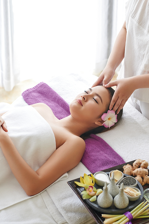 Portrait of attractive young woman getting massage treatment while spending weekend in spa salon