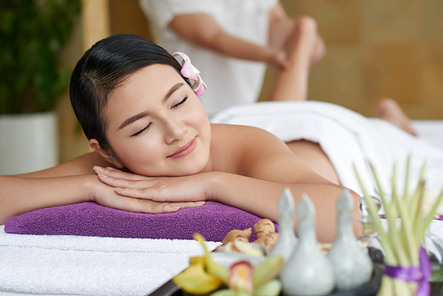 Portrait of pretty woman savoring moment of tranquility while having foot massage in spa salon