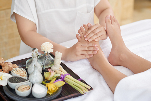 Unrecognizable therapist doing foot reflexology massage at luxurious spa salon