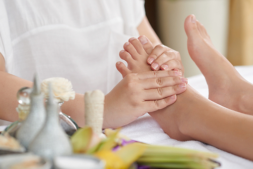 Unrecognizable woman easing muscle tension with help of foot massage at spa salon, close-up shot