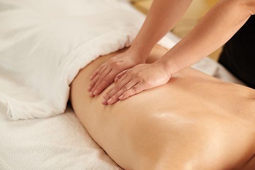 Masseur doing relaxing back massage with oils