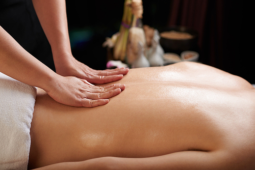 Female hands massaging back of male spa salon client