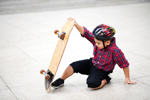 Boy in helmet falling from the skateboard