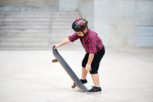 Little boy learning how to ride on skateboard