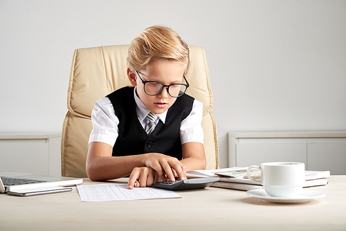 Portrait of little businessman checking financial report at his table