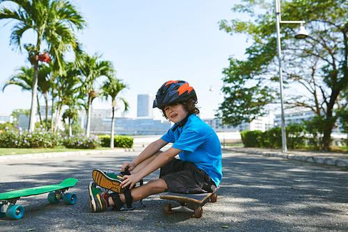 Cute little boy in a helmet sitting on skateboard