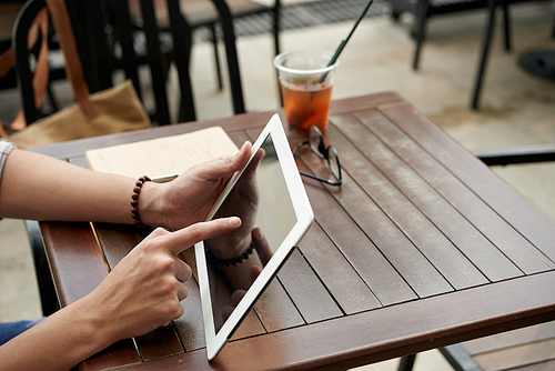 Close-up image of person using application on digital tablet when sitting in cafe