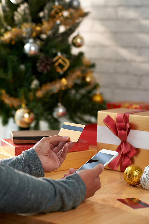 Man using mobile application and credit card to buy Christmas gifts