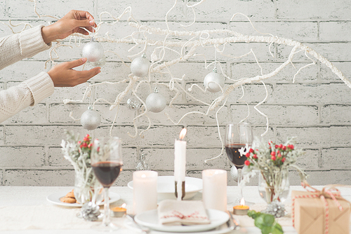 Woman hanging silver baubles to decorate room for Christmas dinner