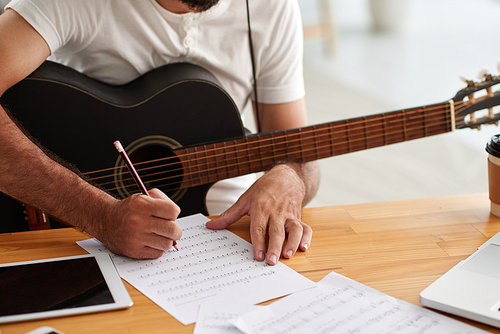 Close-up image of man writing music for new album
