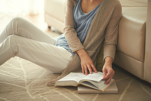 Cropped image of woman sitting on the floor and reading