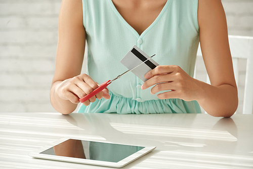 Female shopaholic cutting her credit card with scissors