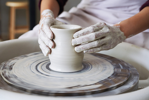 Creative person doing a pot out of white clay