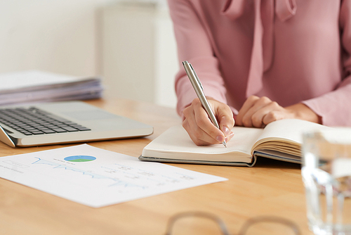 Close-up image of business lady taking notes in her reminder