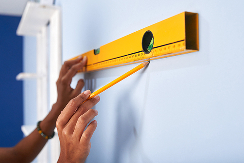 Hands of woman using spirit level to make a mark on the wall