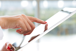 Close-up shot of unrecognizable white collar worker using digital tablet while working at office, blurred background