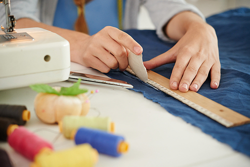 Seamstress using ruler to draw a straight line on fabric