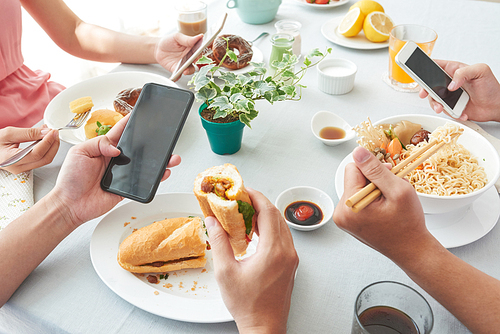 Group of people eating and checking smartphones