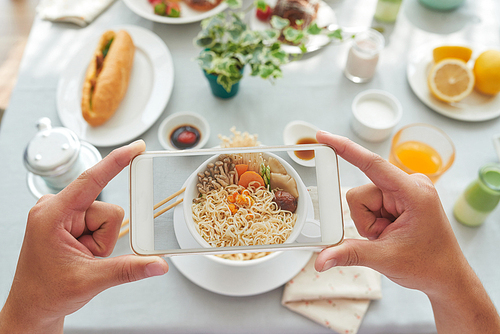 Person photographing noodles with mushrooms on smartphone