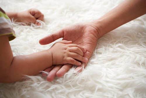 Close-up image of mother holding hand of her little child