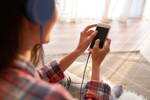 Woman listening to music on smartphone, view over the shoulder