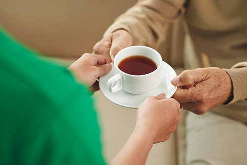 Nurse giving cup of tea to aged man, view from above