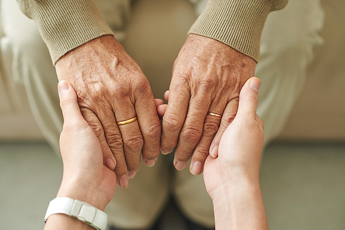 Close-up image of granddaughter holding hands of senior man