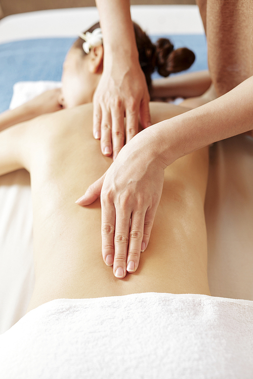 Masseur massaging skin along spine of female client